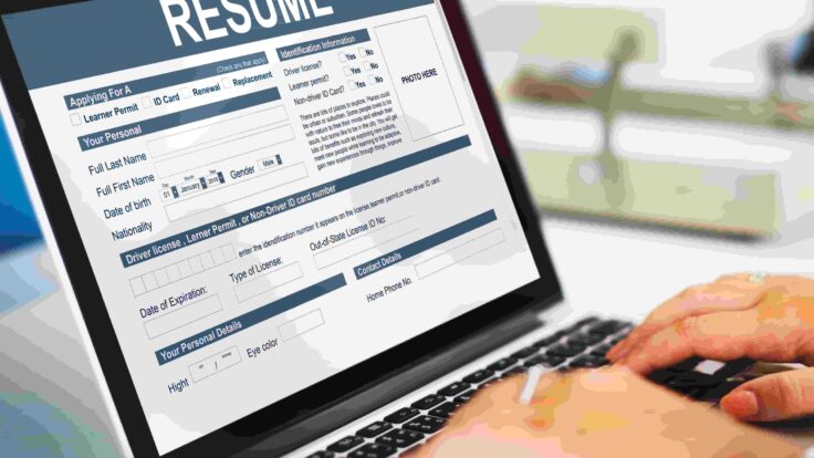 Uma pessoa digitando em um laptop com um currículo