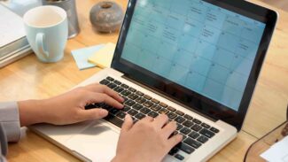 Uma mulher digitando em um laptop em uma mesa