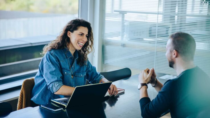 Um homem e uma mulher conversando em uma mesa de escritório