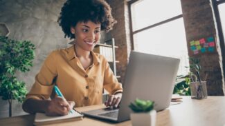Uma mulher sentada em uma mesa com um laptop à sua frente