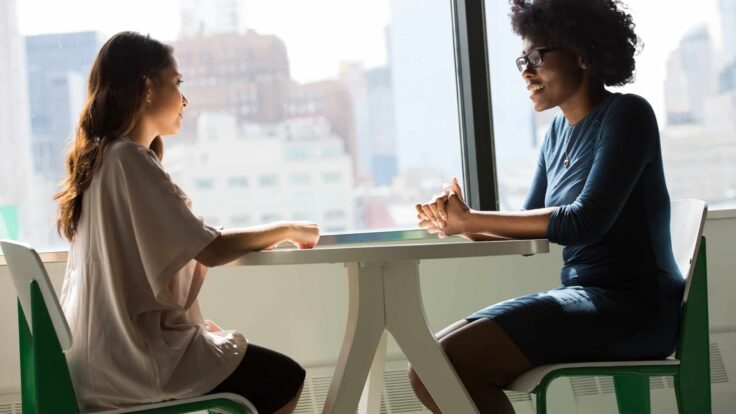 Duas mulheres conversando em uma mesa de escritório