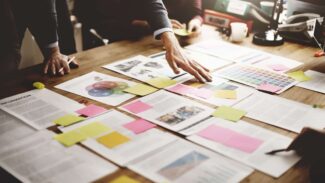 Um grupo de pessoas sentadas ao redor de uma mesa com post-its.