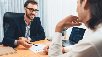 Dois empresários sentados em uma mesa conversando entre si.