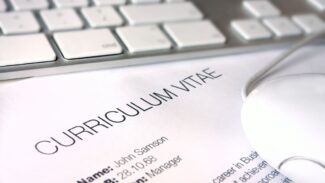 Um mouse de computador fica em cima de um papel com a palavra curriculum vitae