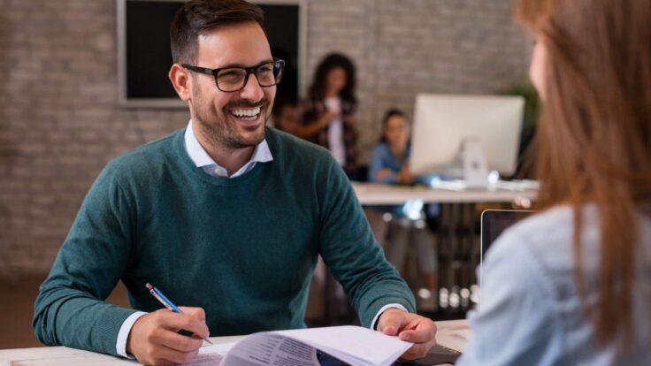 Um homem e uma mulher sorrindo um para o outro em um escritório