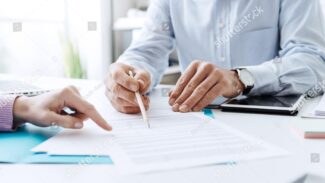 Foto de dois empresários assinando um contrato no escritório.