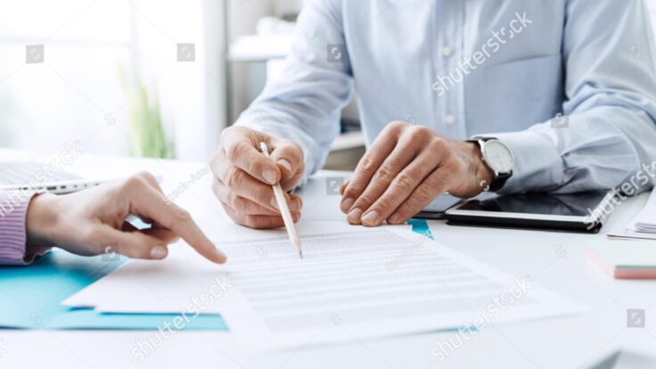 Foto de dois empresários assinando um contrato no escritório.