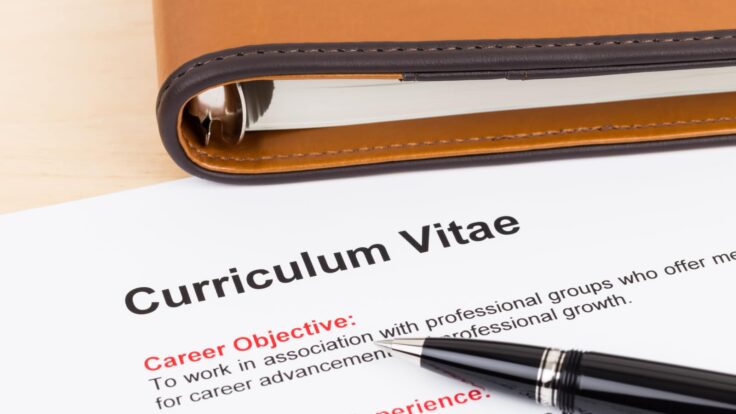 Uma caneta fica em cima de um papel com a palavra curriculum vitae
