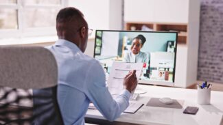 Um homem está usando um computador para fazer uma videochamada.