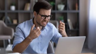 Um homem está gritando com seu laptop no escritório