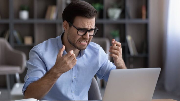 Um homem está gritando com seu laptop no escritório
