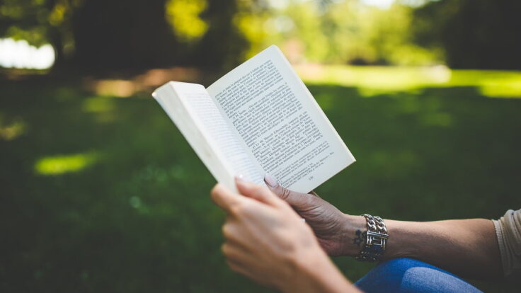 Uma mulher lendo um livro em um parque.
