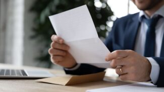 Um homem de terno segura um pedaço de papel