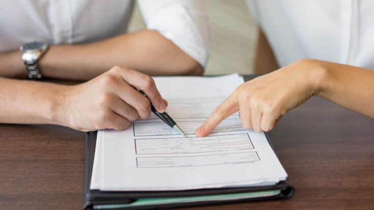 Duas pessoas assinando um documento em uma mesa