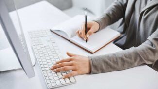 Uma mulher escrevendo em um caderno em uma mesa