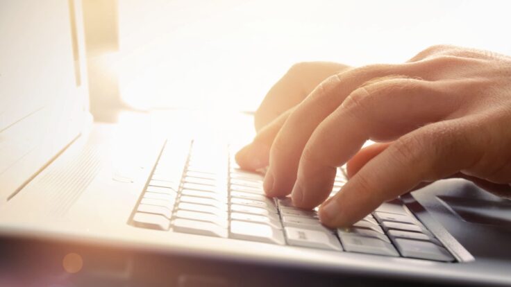 Uma pessoa digitando no teclado de um laptop